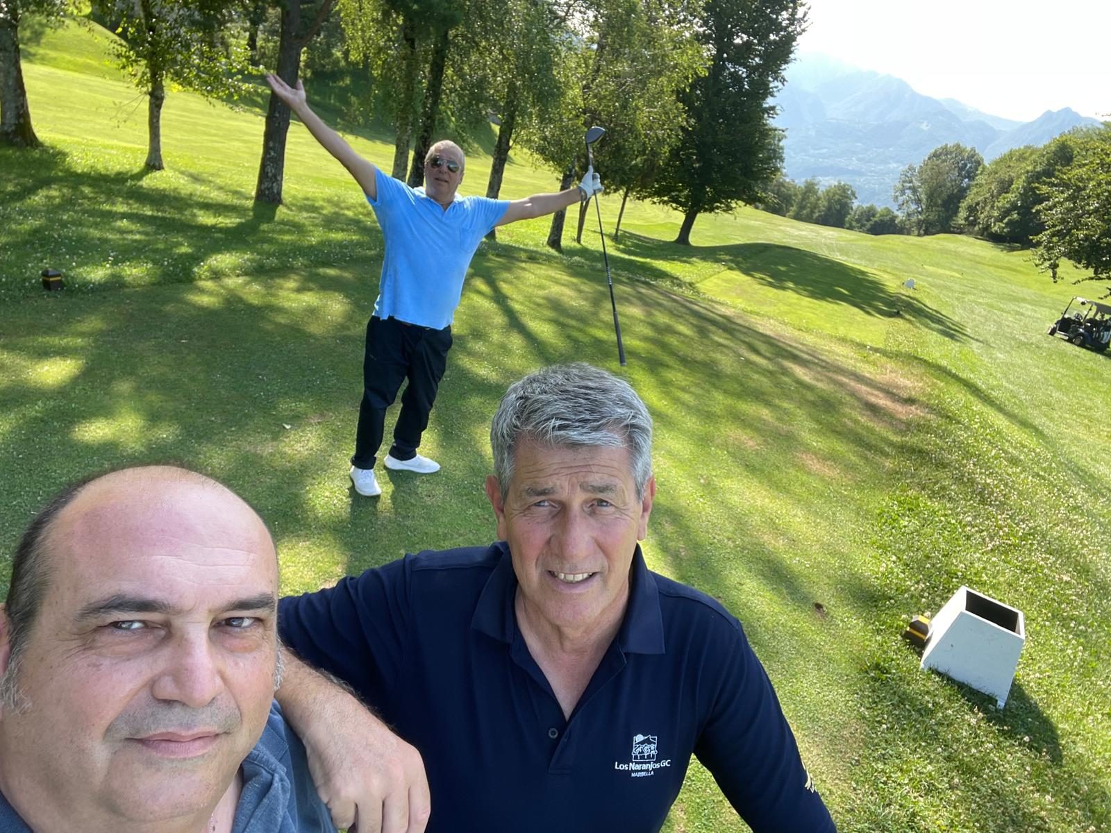 Due giocatori in un selfie sul fairway, sullo sfondo un compagno esulta